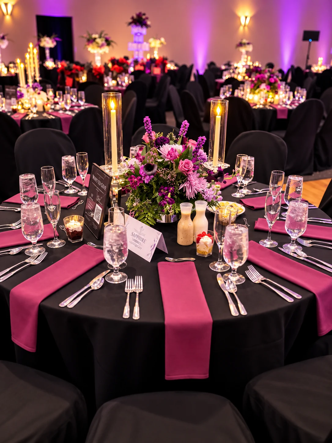 Round gala table styled with pillar candles, plum napkins and event signage — Corporate & Brand Experiences by Good Time Mascots in Columbus, Ohio