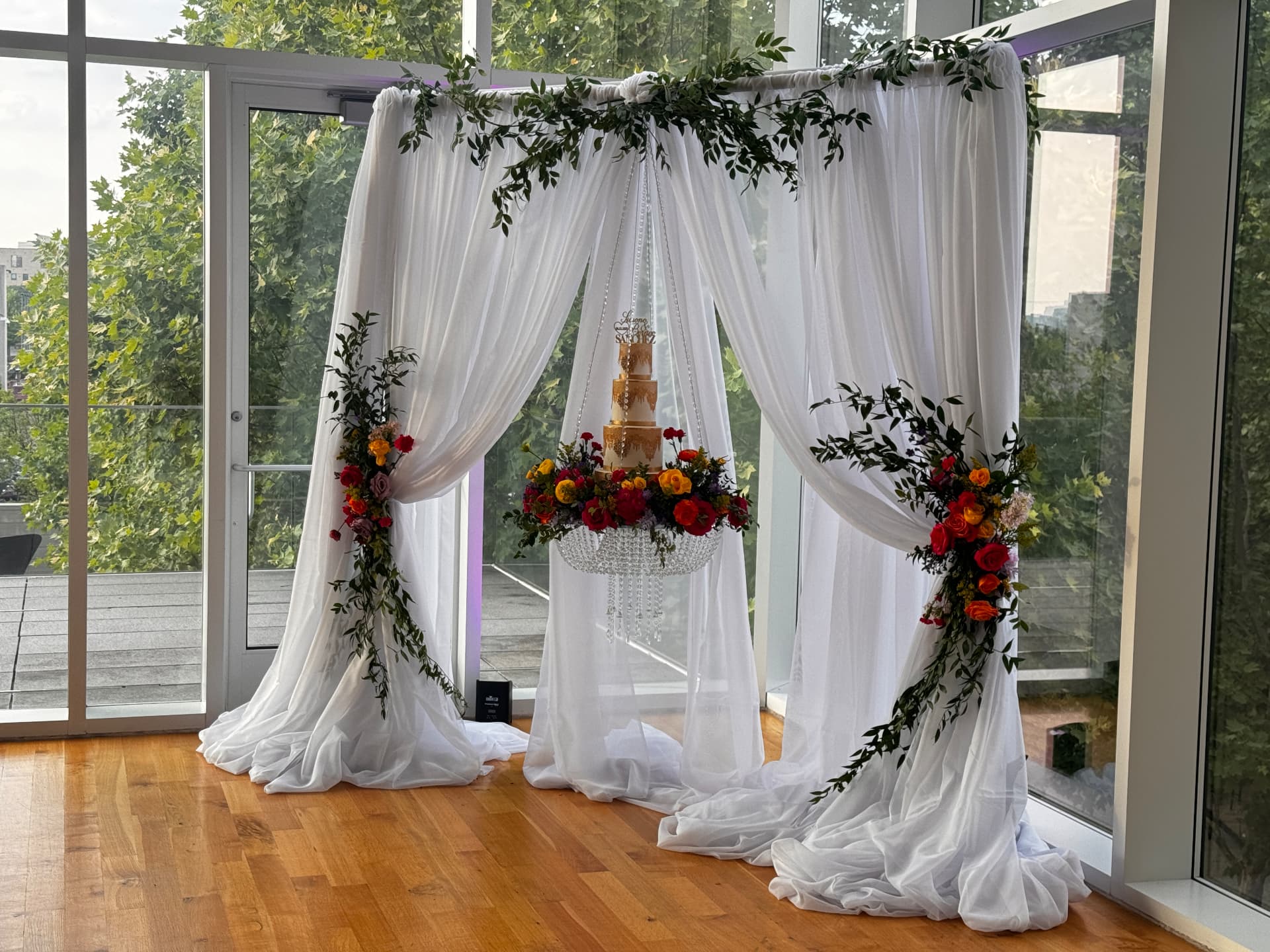 Cake suspended in a crystal tray beneath a greenery-draped canopy — Weddings by Good Time Mascots in Columbus, Ohio
