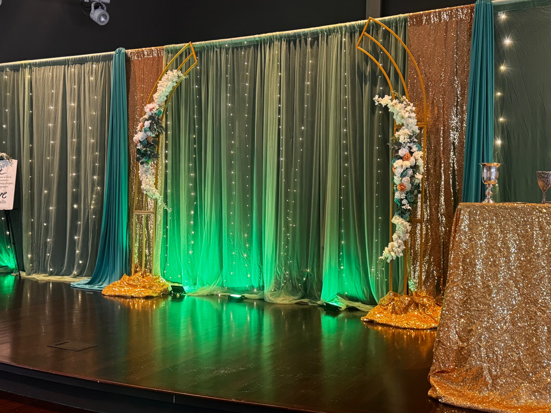 Emerald and gold ceremony stage with floral arches and fairy lights — Weddings by Good Time Mascots in Columbus, Ohio